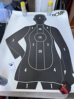 Full view of RCMP silhouette target with scale items around