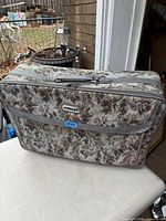 Front view showing floral tapestry exterior, zippered front pocket, and handle