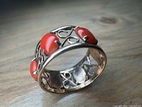 Angled view showing openwork 10k gold band and coral cabochons
