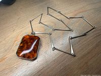 Amber pendant necklace full view on wood surface