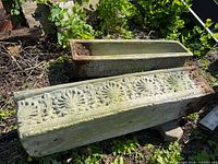 Two rectangular concrete planters showing exterior decorative floral pattern