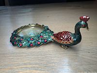 Side profile of peacock-shaped magnifying glass showing body, tail, rhinestones