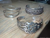 All three sterling cuff bracelets on tabletop