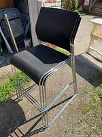 Three black stacking bar stools with chrome bases