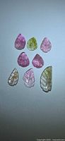 Seven multicolored leaf-cut tourmalines on light background