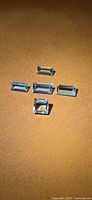 Five rectangular pale blue aquamarine stones on brown background