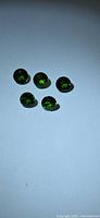 Five green round gemstones on white background