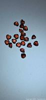 Group of small heart-cut orange-red garnets on light background