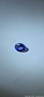 Top view of loose oval violet-blue Tanzanite on neutral background