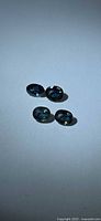 four oval green-blue sapphires on neutral background