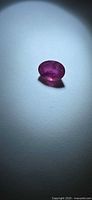 Oval pink sapphire on neutral background under spotlight