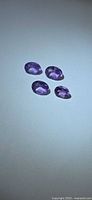 Four oval purple gemstones on neutral background