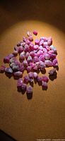 group of rough pink ruby crystals on brown surface