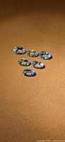 Six oval-cut pale blue aquamarine gemstones on brown surface