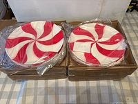Two stacks of red and white peppermint swirl plates in boxes