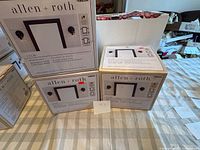 Three sealed Allen + Roth Ullie wall sconce boxes on table