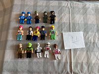 All fifteen minifigures laid out in three rows on fabric background