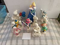 Group view of nine Snowbabies figurines on checkered surface