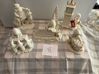 Group view of six Snowbabies figurines on check cloth