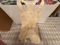 Beige ribbed sleeveless bodysuit laid flat with size note