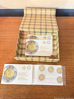 Open plaid box showing three sealed coin booklets and one booklet opened to reveal coins