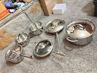 All four pots/pans with lids displayed on carpet