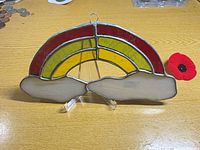 Front view of stained glass rainbow suncatcher showing colored arcs, cloud panels, and hanging loop