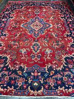 Full view of red Persian rug showing central medallion and blue floral border