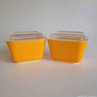 Pair of yellow Pyrex refrigerator dishes with lids front view
