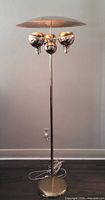 Full view of chrome floor lamp showing base, pole, triple globes and disc shade