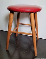 Stool front view shows legs, wood finish, red vinyl seat
