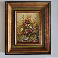 Front view of framed oil painting of wildflowers, signature visible