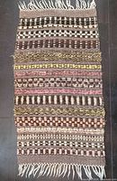 Full view of the small hand-woven rug showing overall pattern and fringe