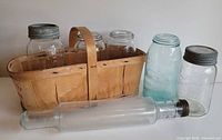 Group shot of basket holding four lidded jars, two additional jars, and glass rolling pin