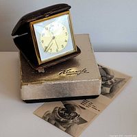 Clock in open case atop original box and leaflet