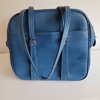 Front view of blue rectangular bag with straps and front slip pocket