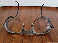 Front view of metal safety glasses showing round lenses and mesh brow guard