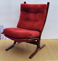 Front perspective of chair showing red tufted cushions and bentwood frame