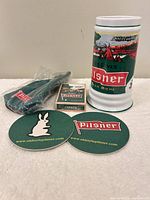 Group shot of all five items: stein, coasters, playing cards, necktie