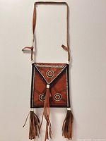 Full view of leather bag showing shape, strap and fringe