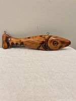 Full left-side view of carved wooden fish club showing overall shape