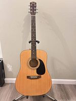 Front view of acoustic guitar showing body, bridge, strings, pickguard