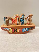 Front view of wooden First Nations style block toy showing base and five fitted animal blocks
