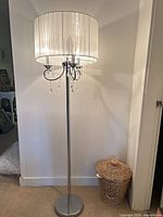 Full view of chrome floor lamp against wall