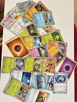Spread of 24 assorted Pokémon cards showing mix of Pokémon, Trainer and Energy cards