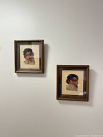Both framed needlepoints hanging on wall showing subjects and frames