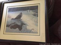 Framed numbered print depicting a rough-legged hawk in a snowy landscape, showing overall condition and framing.