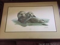 Framed sea otter numbered print, shows two sea otters in water, overall view