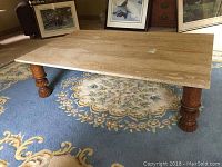 Full view of rectangular marble coffee table showing the smooth marble top and carved wooden legs on a blue floral carpet.