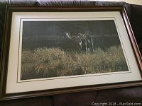 Framed print showing the entire artwork including matte and frame with moose in grass.